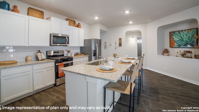 kitchen featuring stainless steel appliances, dark wood-type flooring, sink, a center island with sink, and white cabinets