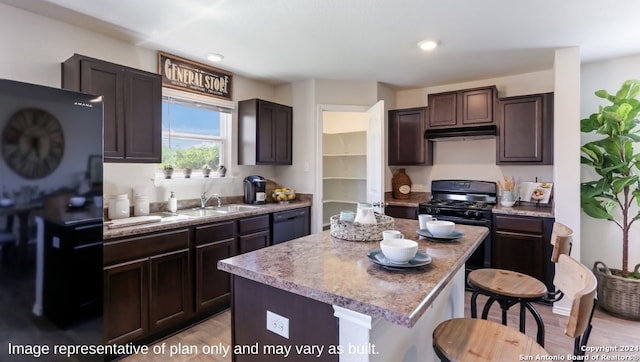 kitchen with a center island, sink, light wood-type flooring, dark brown cabinetry, and a breakfast bar area