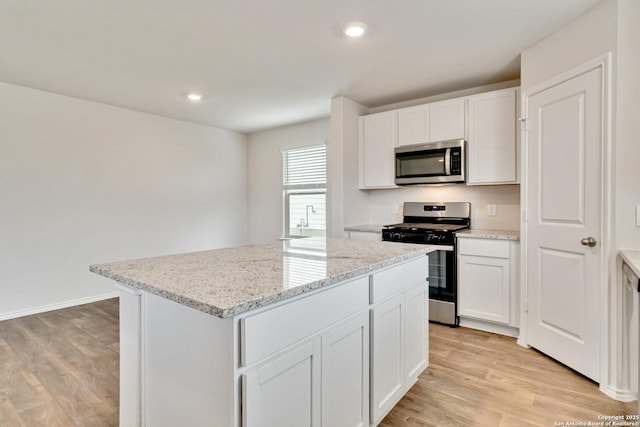 1205 Pacific Monarch, San Antonio, TX 78253 - kitchen featuring appliances with stainless steel finishes, a center island, light wood finished floors, white cabinetry, and light stone counters