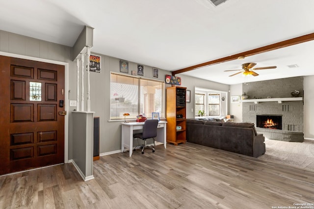 interior space featuring a fireplace, beam ceiling, hardwood / wood-style flooring, and ceiling fan