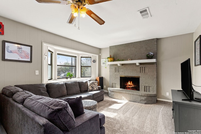 living room featuring carpet, ceiling fan, and a brick fireplace