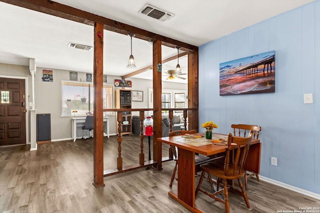 dining space featuring hardwood / wood-style flooring, plenty of natural light, wood walls, and ceiling fan