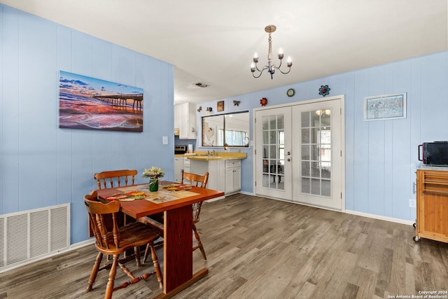 dining space featuring hardwood / wood-style floors, a notable chandelier, sink, and french doors