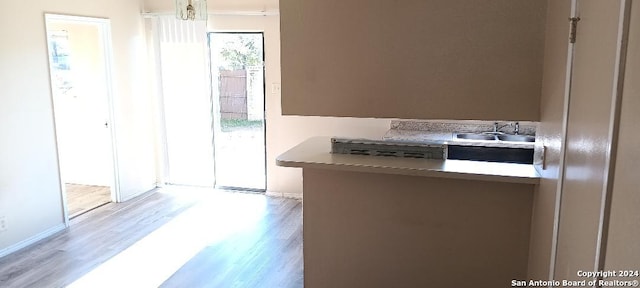 kitchen with kitchen peninsula, sink, and light wood-type flooring