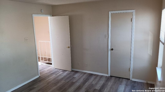 unfurnished bedroom with a textured ceiling and dark wood-type flooring