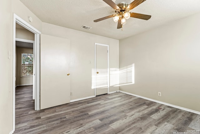 unfurnished bedroom featuring dark hardwood / wood-style floors, ceiling fan, and a textured ceiling