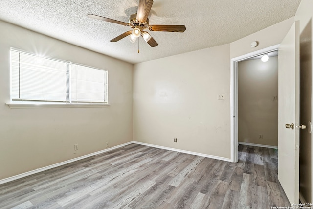 spare room with ceiling fan, light hardwood / wood-style flooring, and a textured ceiling