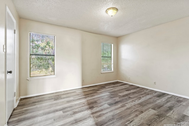 empty room with a textured ceiling and hardwood / wood-style flooring