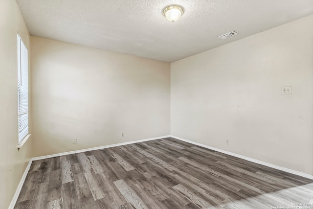 spare room featuring a textured ceiling and dark hardwood / wood-style flooring