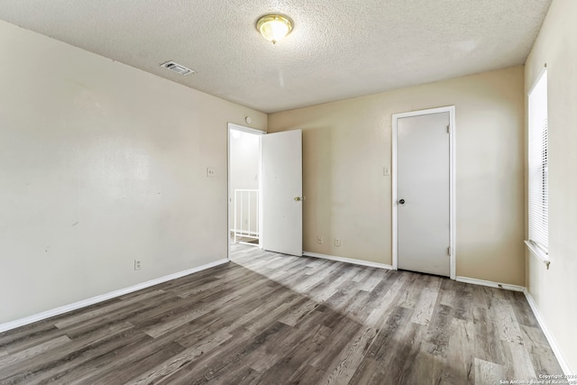 unfurnished bedroom featuring wood-type flooring, a textured ceiling, and a closet