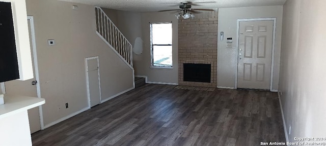 unfurnished living room featuring a fireplace, ceiling fan, dark hardwood / wood-style flooring, and a textured ceiling