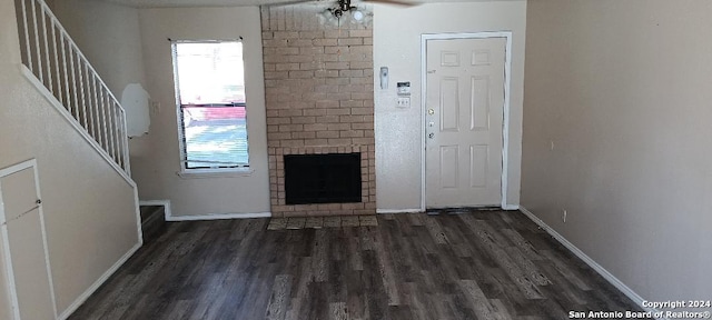 unfurnished living room with dark hardwood / wood-style floors, ceiling fan, and a brick fireplace