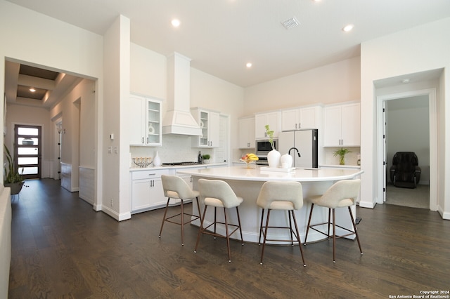 kitchen featuring custom exhaust hood, a large island with sink, dark hardwood / wood-style flooring, white cabinetry, and stainless steel appliances