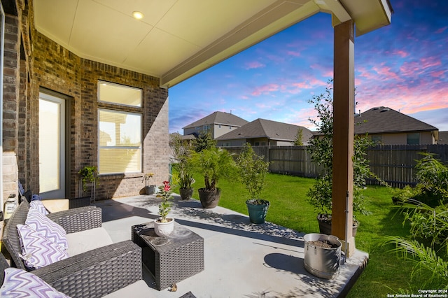 patio terrace at dusk featuring a yard