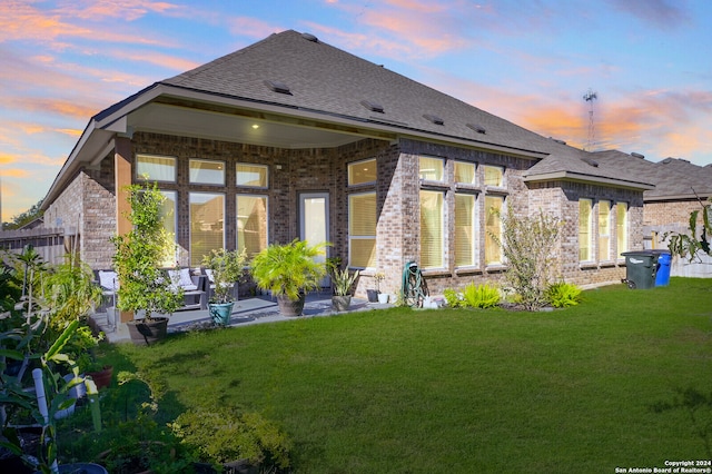 back house at dusk with a lawn