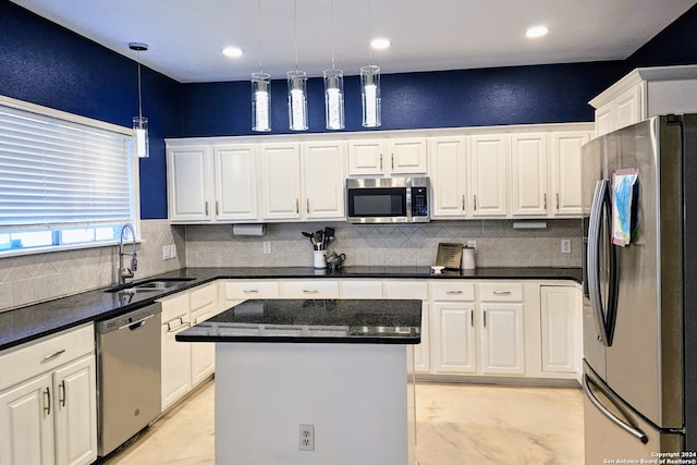 kitchen featuring a center island, sink, stainless steel appliances, pendant lighting, and white cabinets