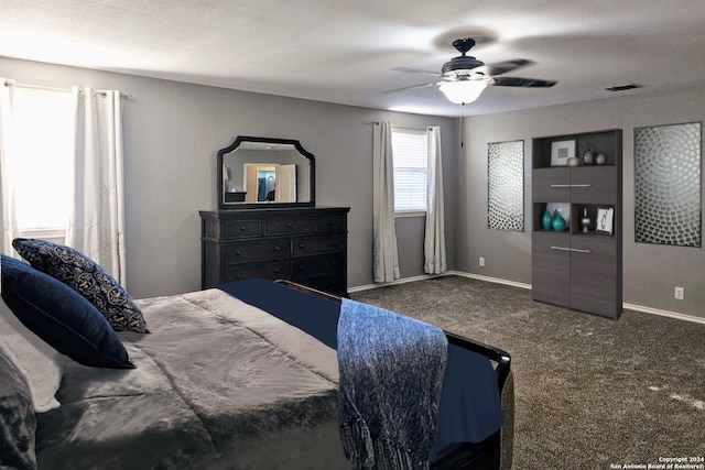 bedroom featuring ceiling fan, dark carpet, and a textured ceiling