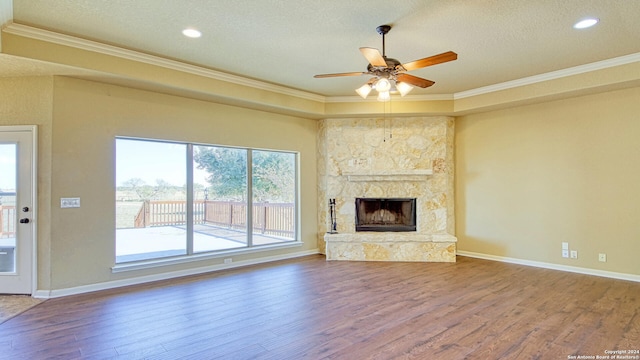 unfurnished living room with ceiling fan, crown molding, hardwood / wood-style floors, a textured ceiling, and a fireplace