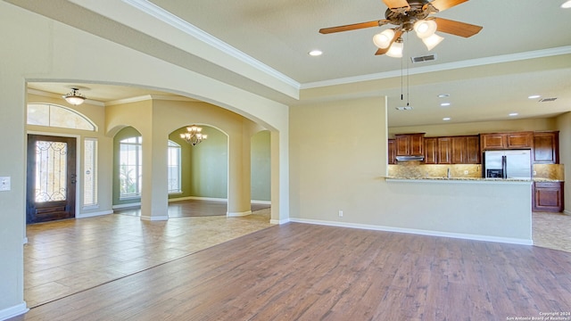 interior space with ceiling fan with notable chandelier, light hardwood / wood-style floors, and ornamental molding