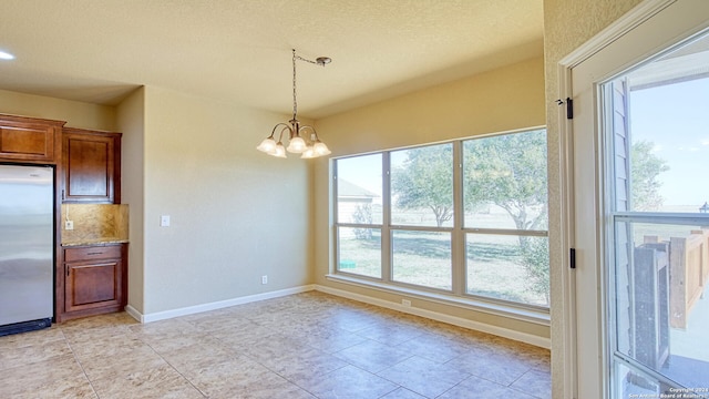 unfurnished dining area with a notable chandelier, light tile patterned floors, and a textured ceiling