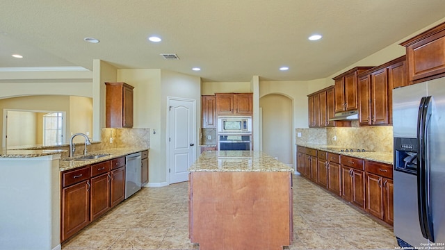 kitchen with light stone counters, sink, a kitchen island, and appliances with stainless steel finishes