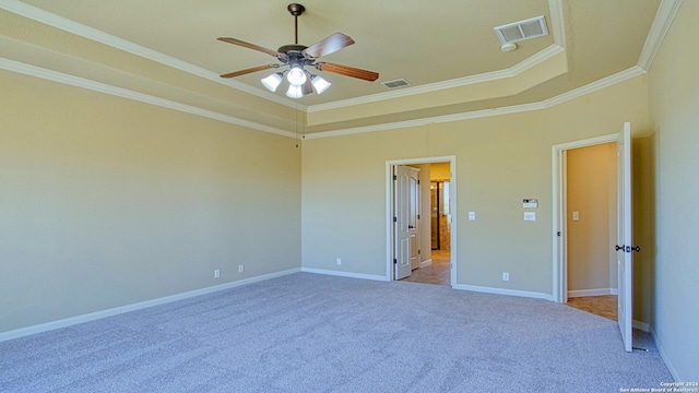 empty room featuring light colored carpet, ceiling fan, a raised ceiling, and ornamental molding