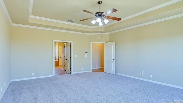 carpeted empty room with a tray ceiling, ceiling fan, and ornamental molding