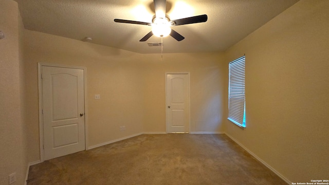 spare room with carpet flooring, ceiling fan, and a textured ceiling