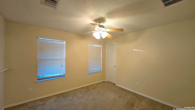 carpeted spare room with a textured ceiling and ceiling fan