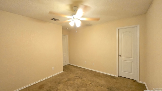 empty room with ceiling fan, light colored carpet, and a textured ceiling