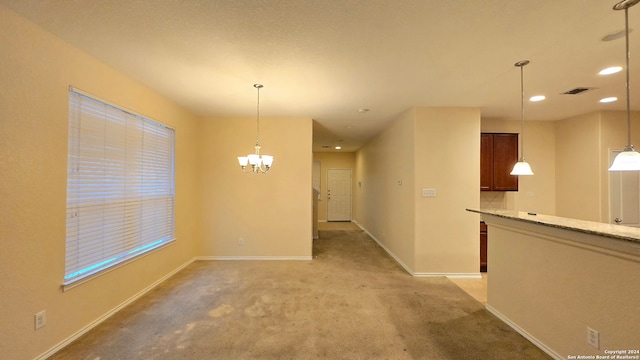 spare room featuring a chandelier and light colored carpet