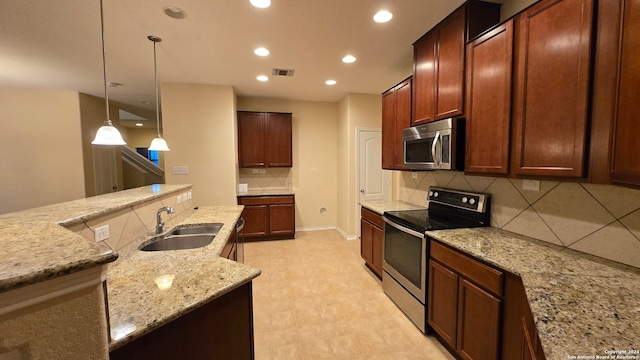 kitchen with appliances with stainless steel finishes, backsplash, light stone counters, sink, and decorative light fixtures