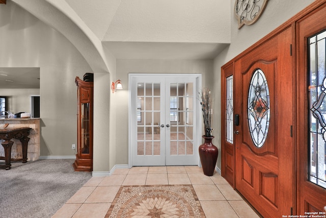 foyer featuring french doors, light tile patterned floors, and a textured ceiling