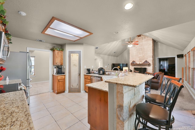 kitchen with a breakfast bar, light colored carpet, appliances with stainless steel finishes, and vaulted ceiling