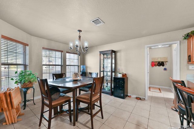 tiled dining area featuring a textured ceiling, wine cooler, and a chandelier