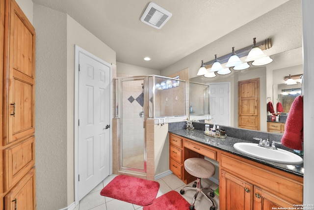 bathroom with tile patterned flooring, vanity, and walk in shower