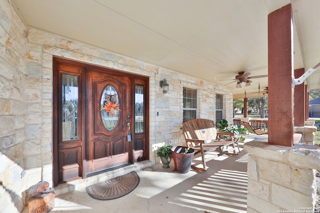 view of exterior entry with ceiling fan and covered porch