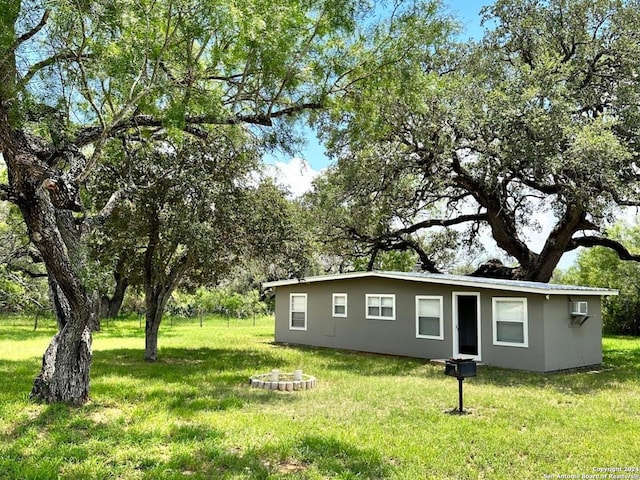 exterior space with a wall unit AC and a front lawn