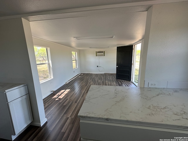 interior space with dark hardwood / wood-style floors, a textured ceiling, and a wall unit AC