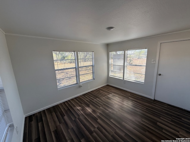 unfurnished room with a healthy amount of sunlight, dark hardwood / wood-style flooring, ornamental molding, and a textured ceiling