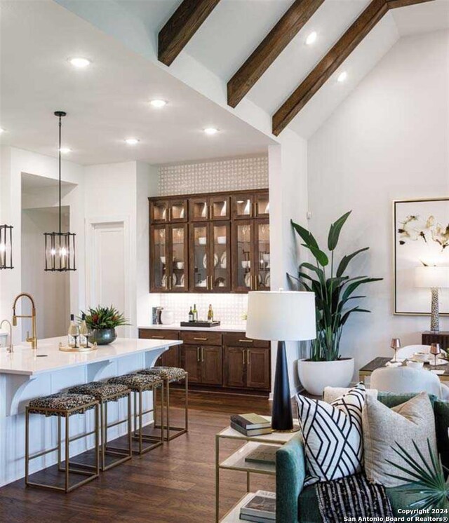 bar featuring dark wood-type flooring, lofted ceiling with beams, hanging light fixtures, decorative backsplash, and dark brown cabinets