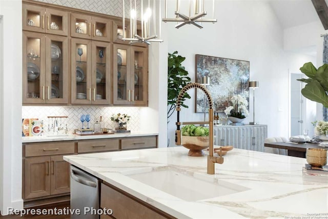 bar featuring sink, decorative light fixtures, light stone countertops, and stainless steel dishwasher