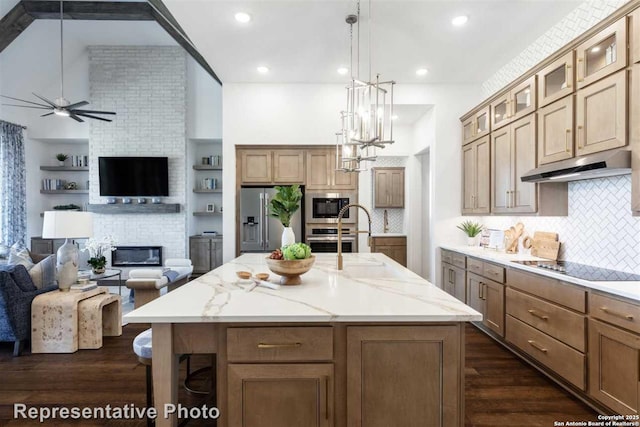 kitchen with black appliances, decorative light fixtures, tasteful backsplash, an island with sink, and light stone counters