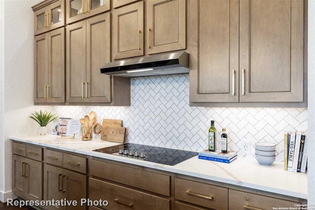 kitchen with backsplash, light stone countertops, and black electric cooktop