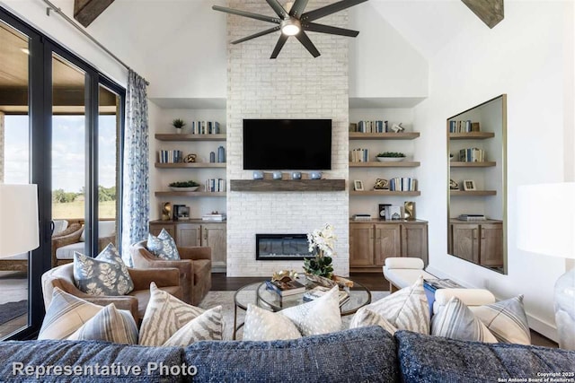 living room with hardwood / wood-style flooring, a brick fireplace, high vaulted ceiling, built in features, and ceiling fan