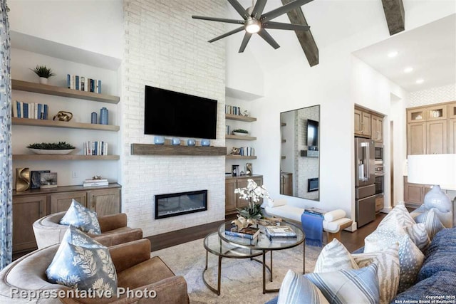 living room with a large fireplace, built in features, light wood-type flooring, high vaulted ceiling, and beam ceiling