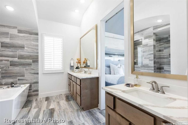 bathroom with a tub, tile walls, vanity, and lofted ceiling