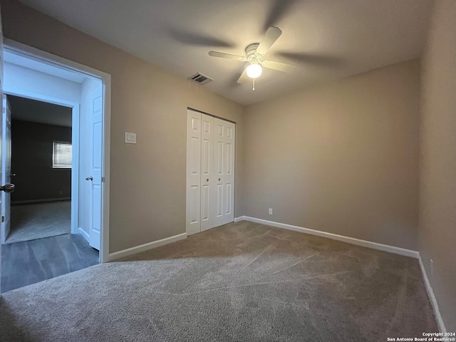 unfurnished bedroom with dark colored carpet, ceiling fan, and a closet