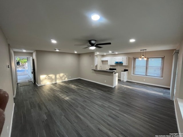 unfurnished living room with ceiling fan and dark wood-type flooring