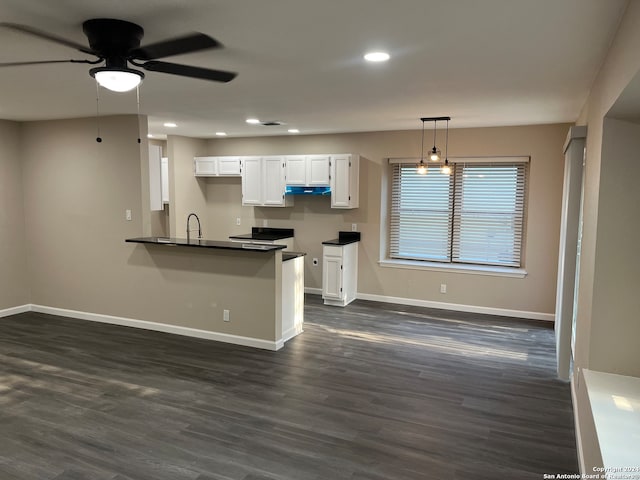 kitchen featuring pendant lighting, dark wood-type flooring, kitchen peninsula, ceiling fan, and white cabinetry